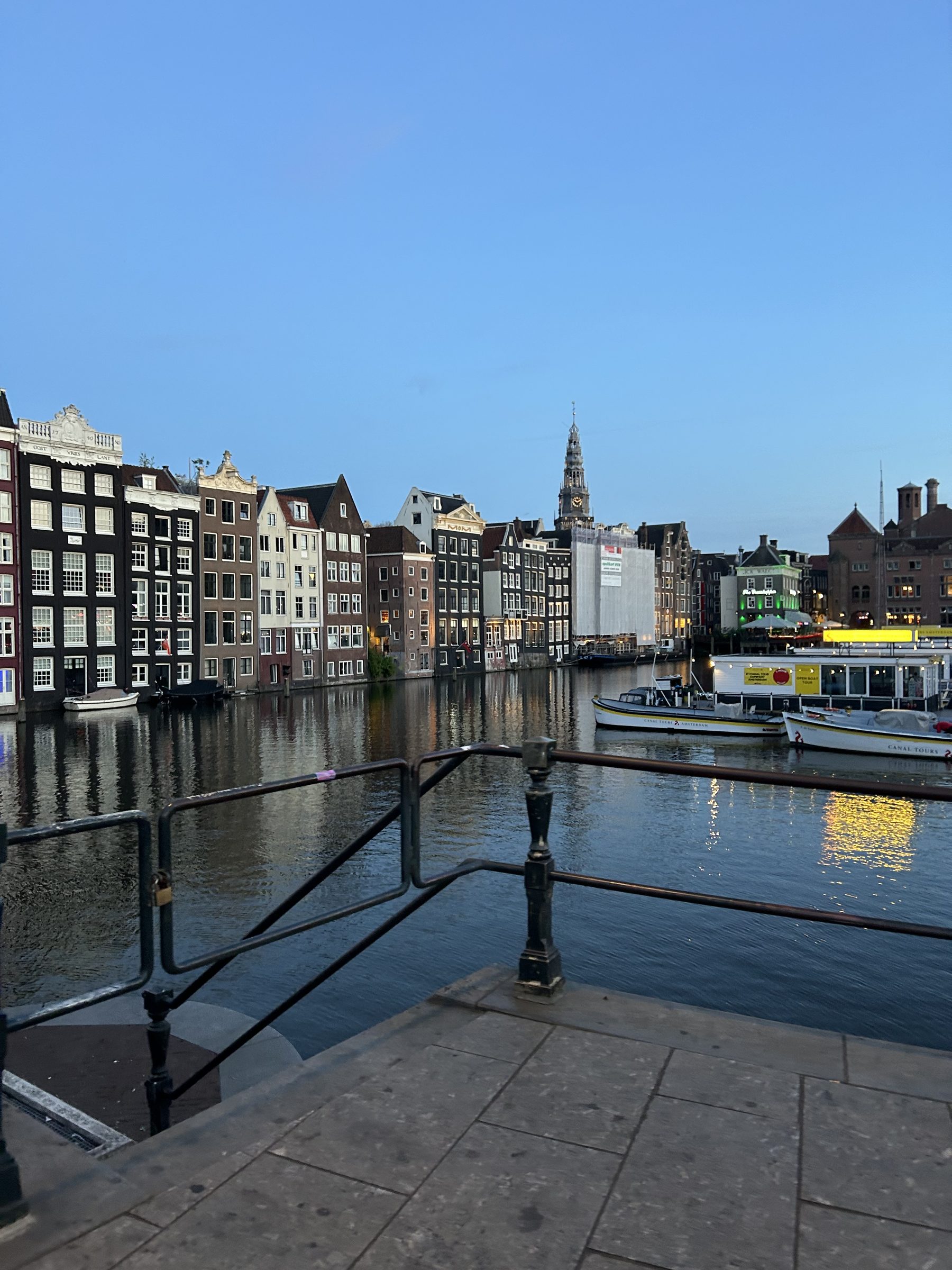 Canal houses along the water in Amsterdam under a clear evening sky