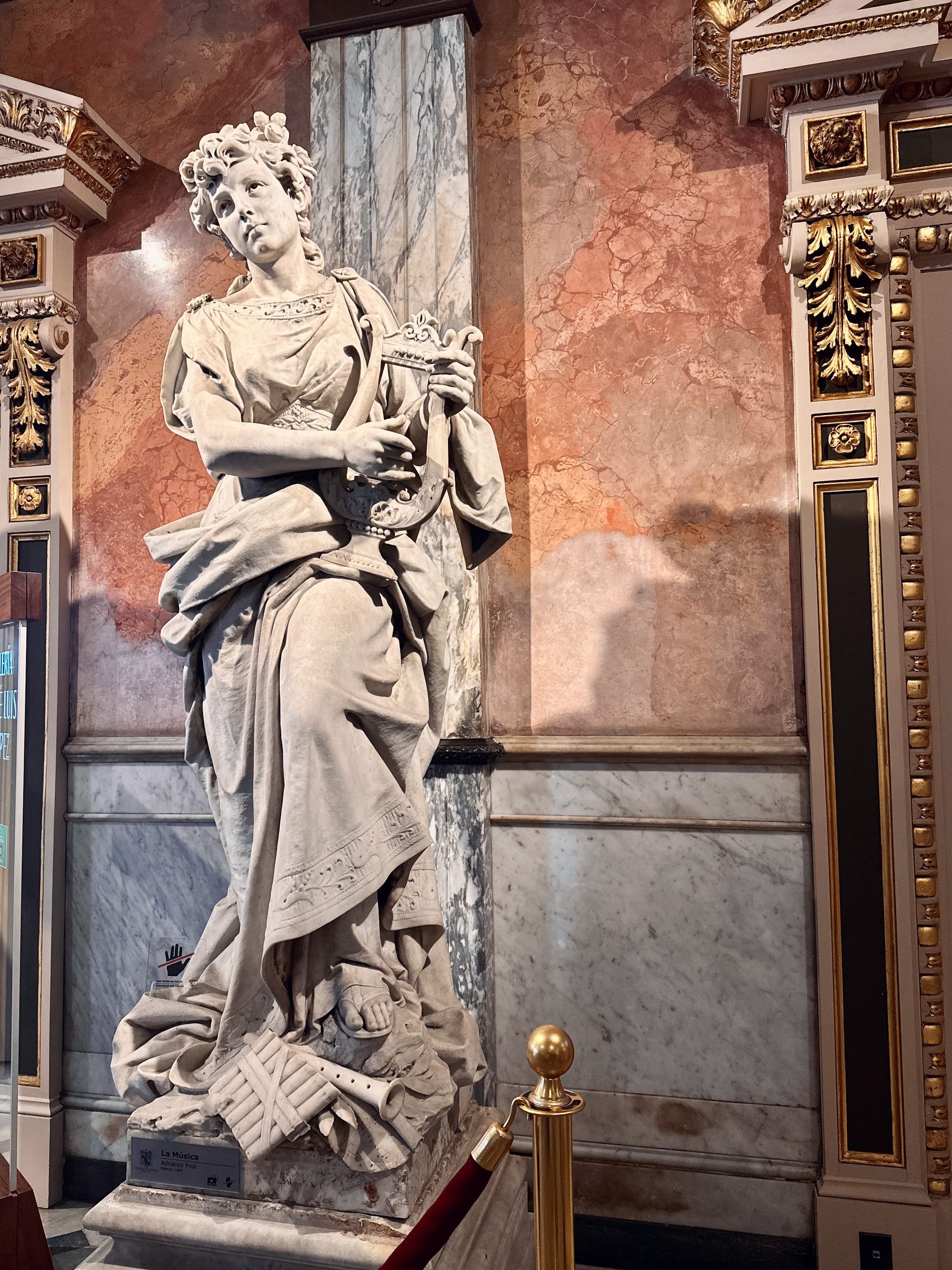 A marble statue of a woman playing a harp in a decorated theatre hall