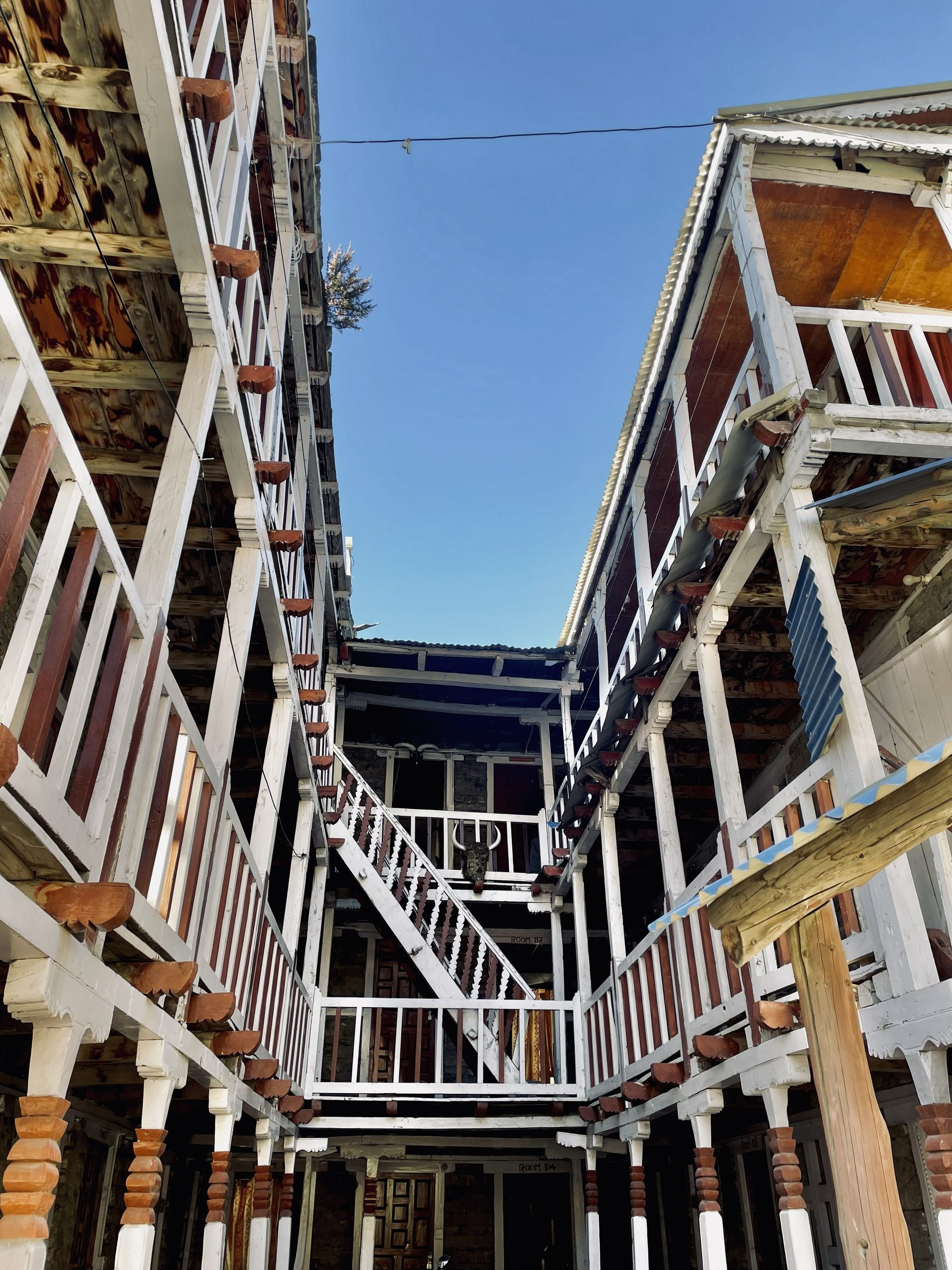 Looking up between the wooden balconies and white rails of a mountain lodge