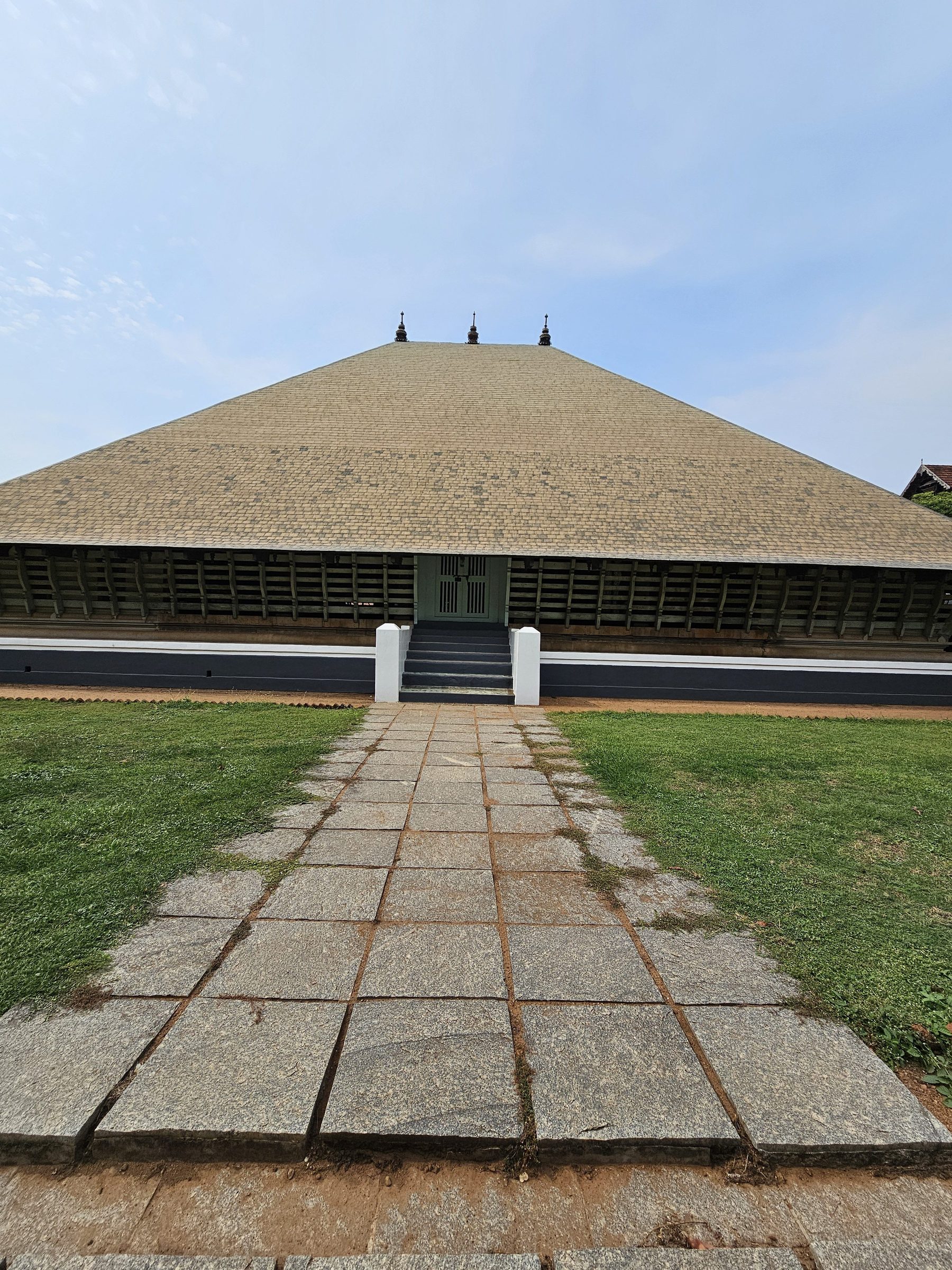 A temple theatre with a wide sloping roof at the end of a stone path